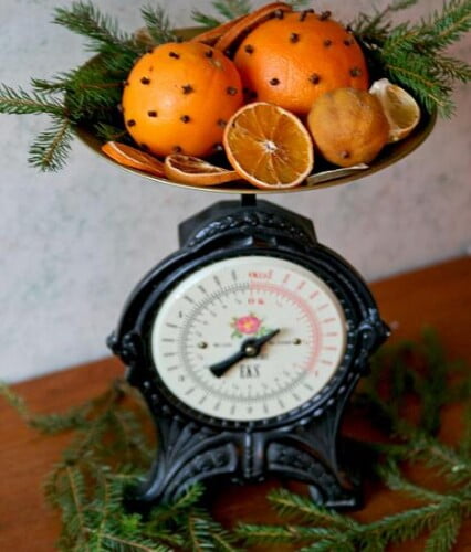 Gammeldags järnvåg med juliga apelsiner med nejlikor i vågskålen.