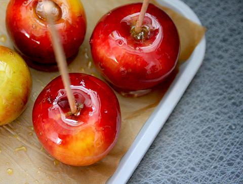 Glansiga röda äpplen som blivit kanderade av socker. Äpplena har en pinne in i frukten som sen ska gå att hålla i. picture-945.jpg