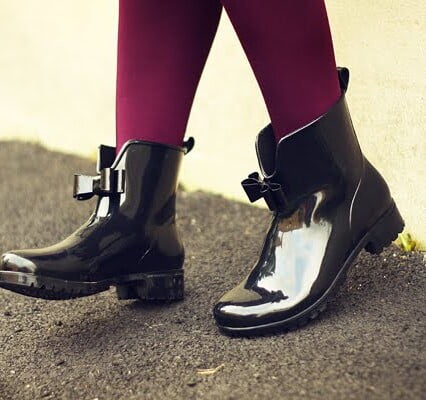 Svarta lackstövletter med rosett vid ankeln.