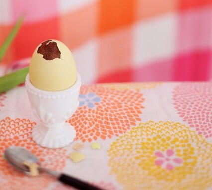 Vanligt äggskal fyllt med choklad istället för vita och gula, i vit skir porslinskopp på färgglad duk.
