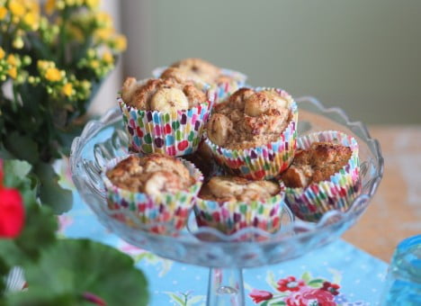 Muffins i färgglada pappersformar i glasfat på fot.