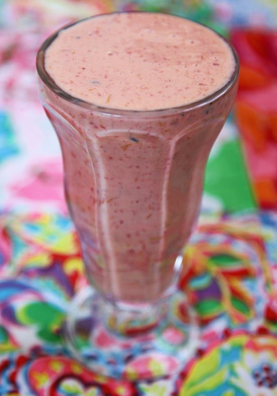 Kraftigt glas  på fot till bredden fyllt med krämig dryck med mixade bär i rött och blått.