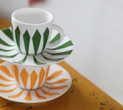 Två färgglada kaffekoppar med dekorerade mönster travade på varandra.