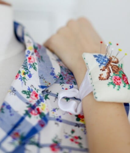 Claras hand med en nåldyna som är fastknuten runt handleden.