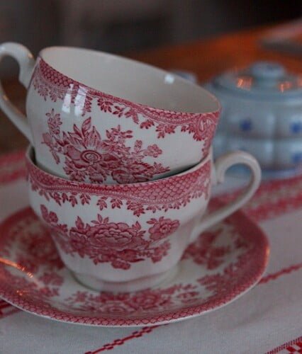 Rosavita tekoppar av engelsk porslin framför blågrå sockerskål.