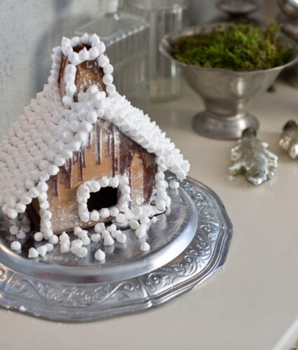 Pepparkakshus dekorerat med vita minimaränger och florsocker.