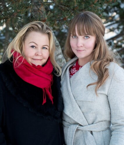 Clara och Erica klädda i vinterkläder framför tallris utomhus, fotat för En Underbar Pod.