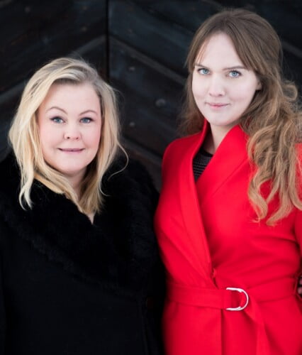 Clara med Erica Dahlgren utomhus i vinterväder. Står framför en mörk trädörr. Clara i röd kappa.