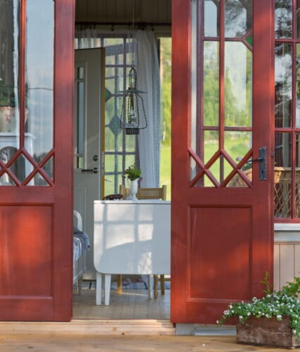 Punchveranda med öppna dörrar i grönska.