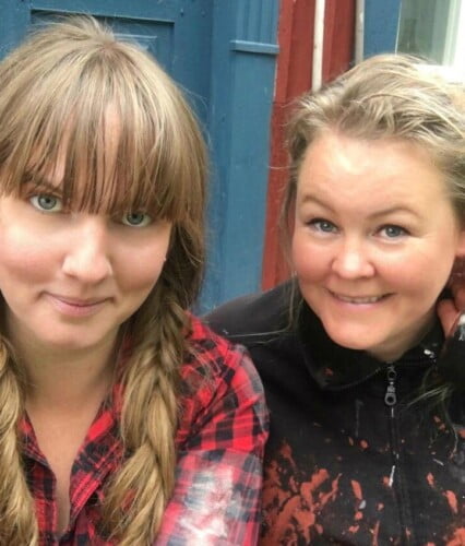 Clara och Erica i färgfläckiga målarklädar, Clara i flätor och Erica med hår uppsatt för arbete. Ur En Underbar Pod, från Ericas fritidshus.