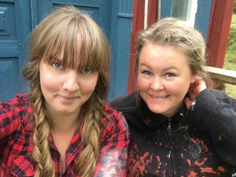 Clara och Erica i färgfläckiga målarklädar, Clara i flätor och Erica med hår uppsatt för arbete. Ur En Underbar Pod, från Ericas fritidshus.