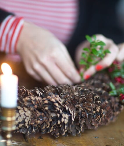 Kottkrans där händer binder fast små kvistar med röda lingon i. Ur En Underbar Pod.