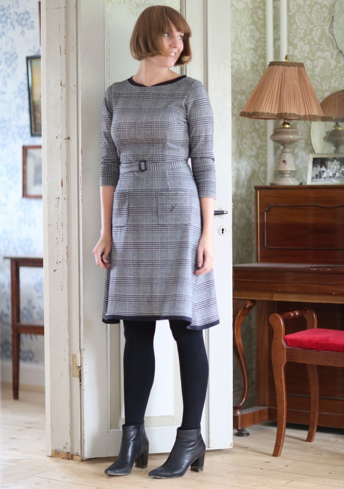 Clara i page och svartvit klänning med rutmönster ler men tittar inte in i kameran.