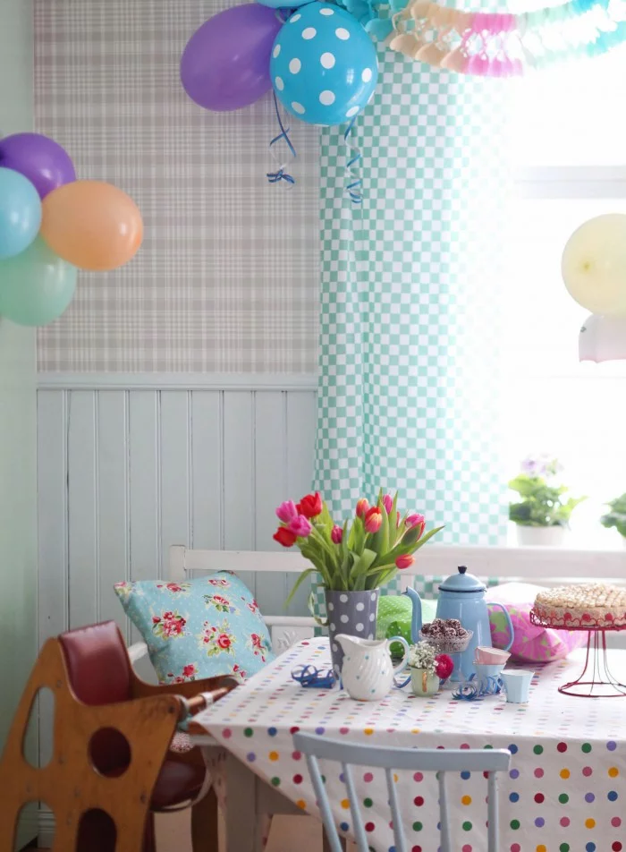 Barnkalasfixat kök med ballonger i fönstret och blommor på bordet.