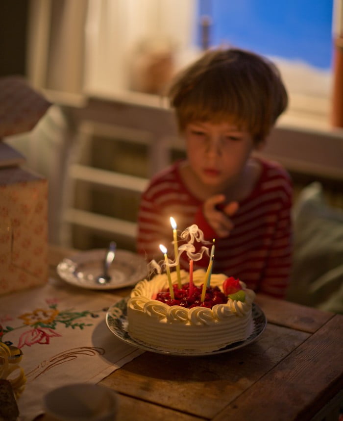 Gryningsljus där Claras son Bertil sitter framför födelsedagstårta med ljus.