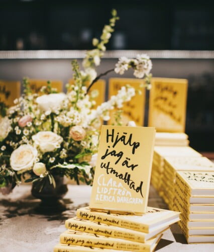 Gula boktravar av boken Hjälp jag är utmattad intill en fin blombukett.